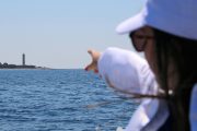girl pointing at veli rat lighthouse during a dugi otok boat tour