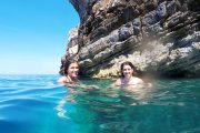 two girls swimming in the sea near clifs