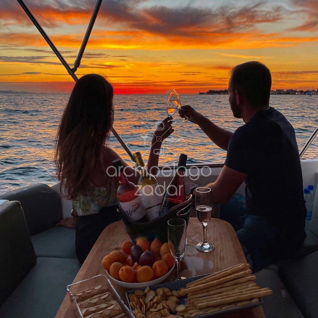 couple watching sunset in zadar archipelago with champagne 