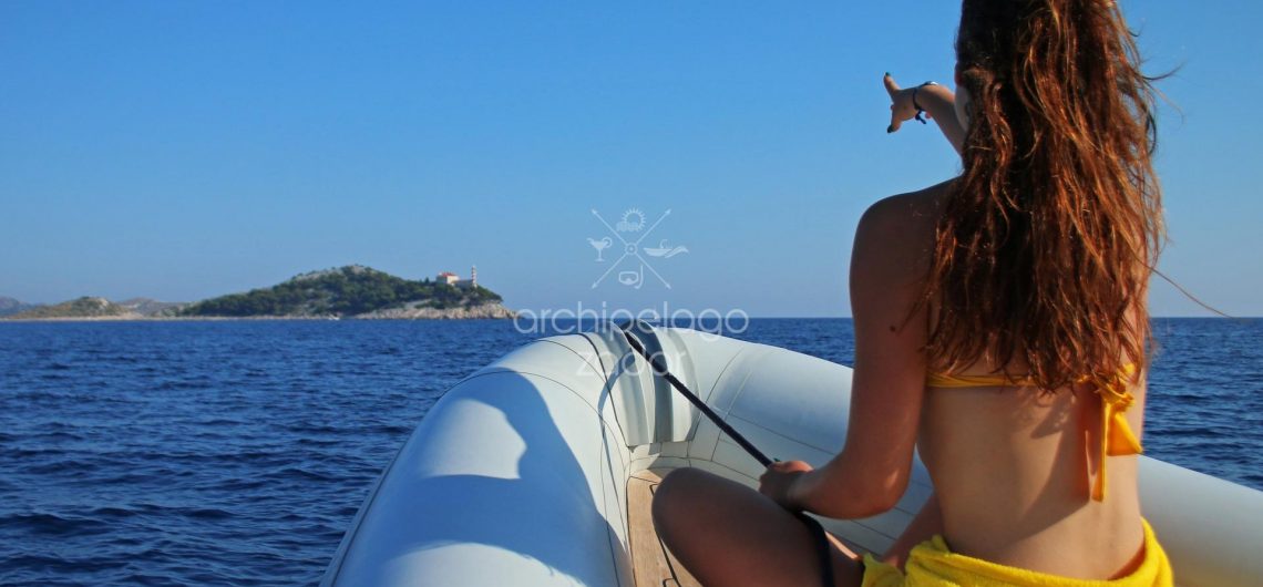 girl in swimsuit on a speedboat pointing to thre island on kornati boat trip