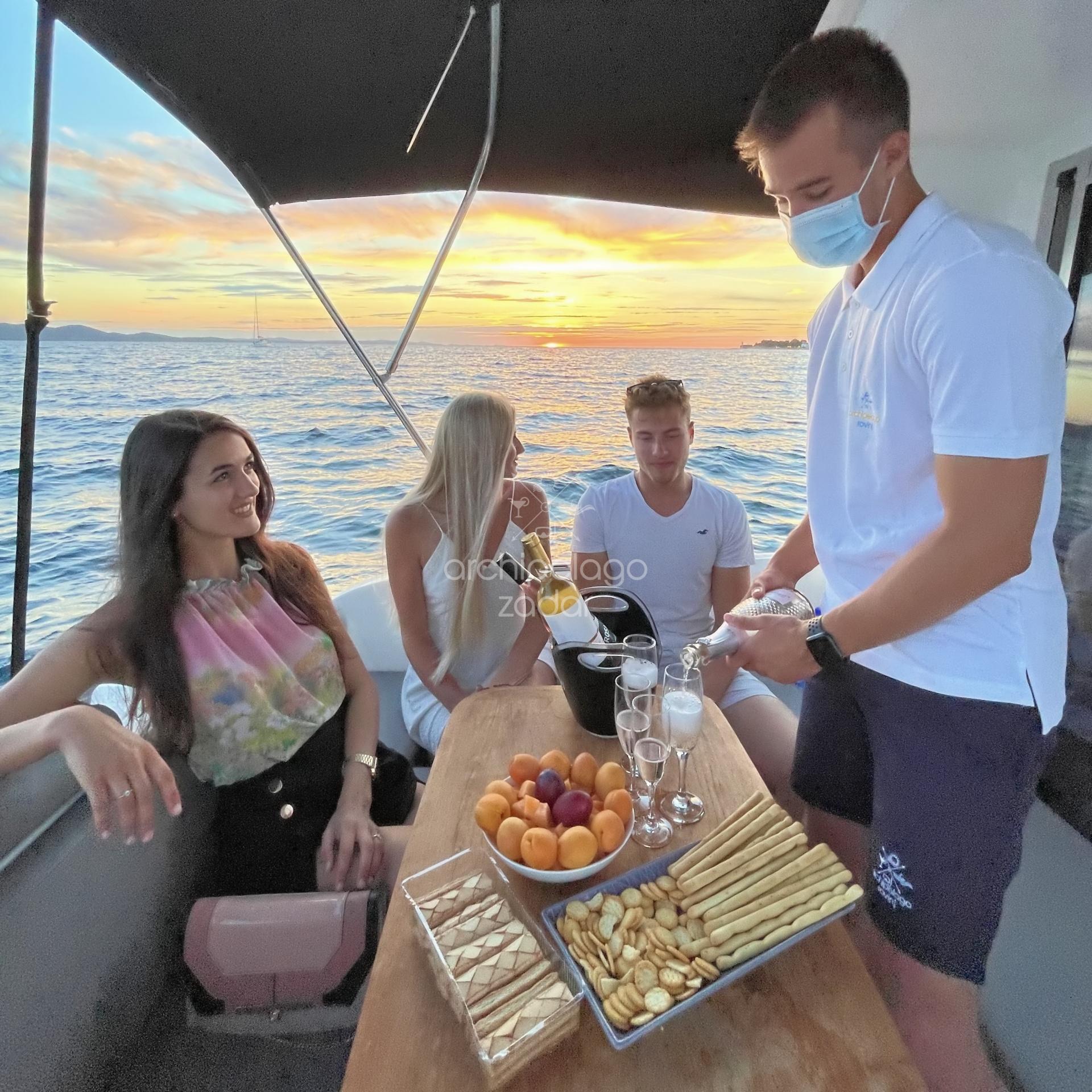 people on boat on sunset drinking champagne skipper serving